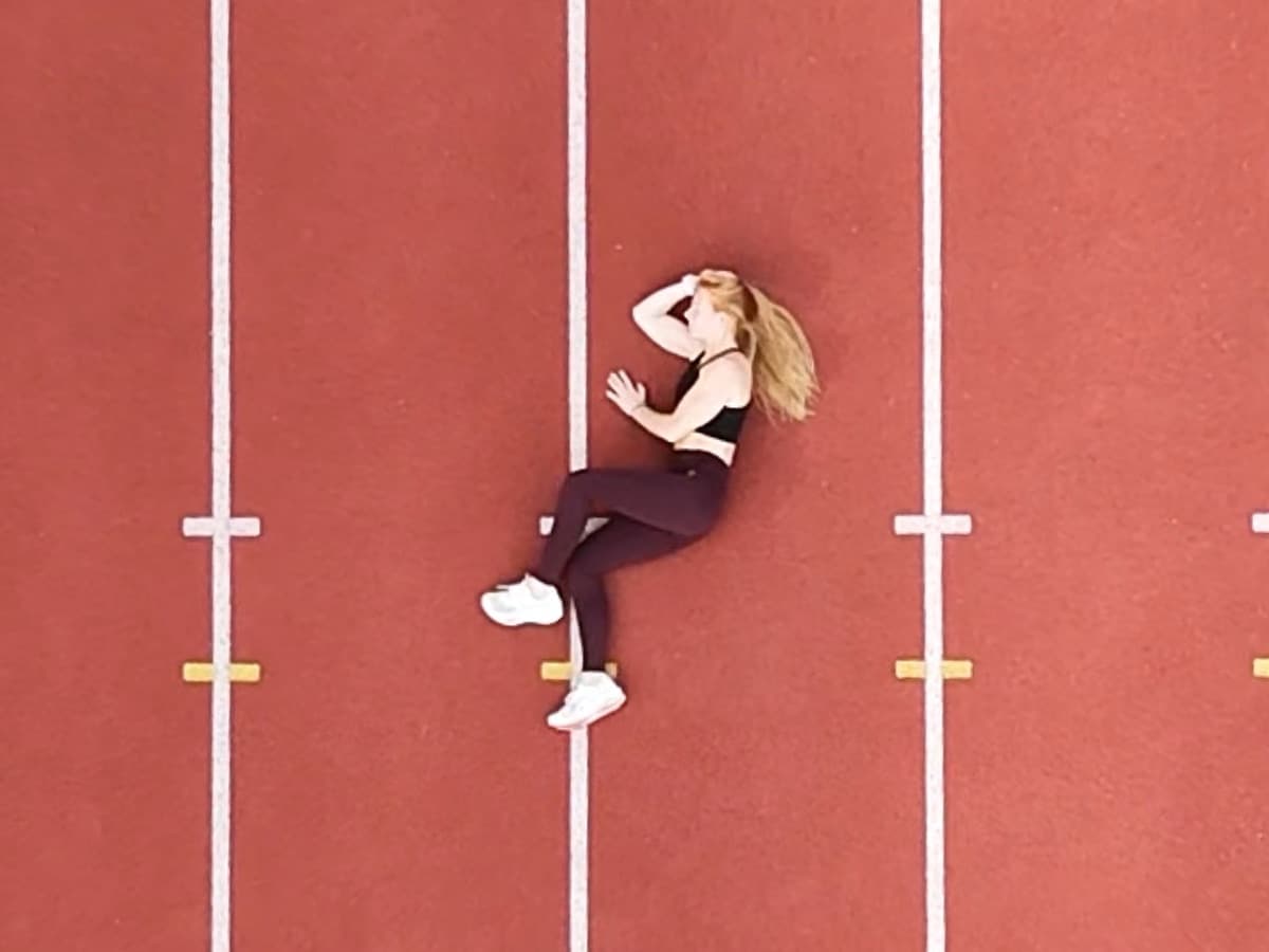 Nolwenn allongée au milieu d'une piste d'athlétisme, vue du ciel